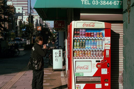 A man using a vending machine on a street in Tokyo, Japan during the day.